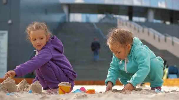 Due bambini di 4-5 anni seduti in sandbox, che giocano con giocattoli e secchi — Video Stock