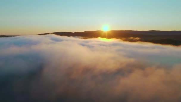 Пролітаючи крізь хмари до гірського хребта на горизонті, сонце світить, схід сонця — стокове відео