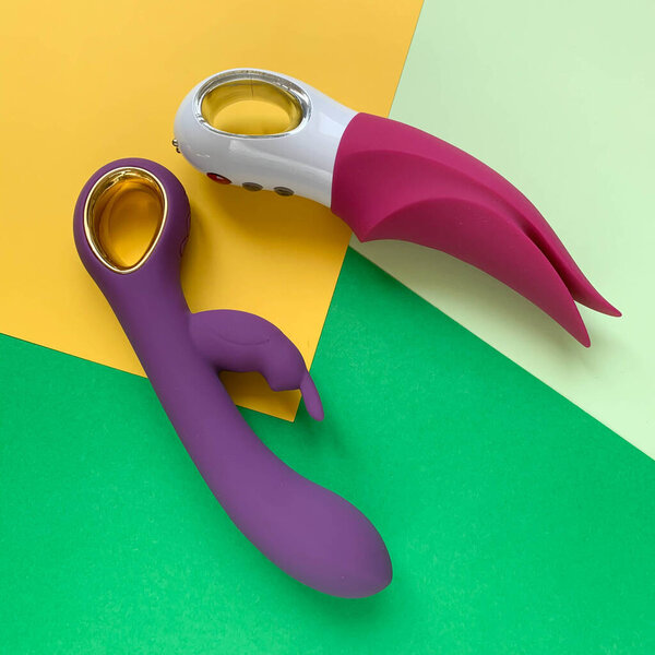 Секс-игрушки. Два вибратора на зелено-желтом фоне. Полезно для взрослых, секс-шоп
