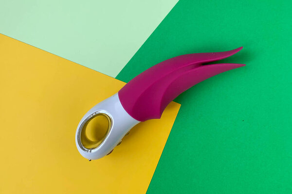 Секс-игрушка. Розовый вибратор на цветном фоне. Полезно для взрослых, секс-шоп
