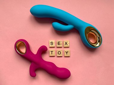 Seks oyuncakları. Pembe arka planda iki vibratör. Yazılı seks oyuncağı. Yetişkinler için kullanışlı, seks dükkanı