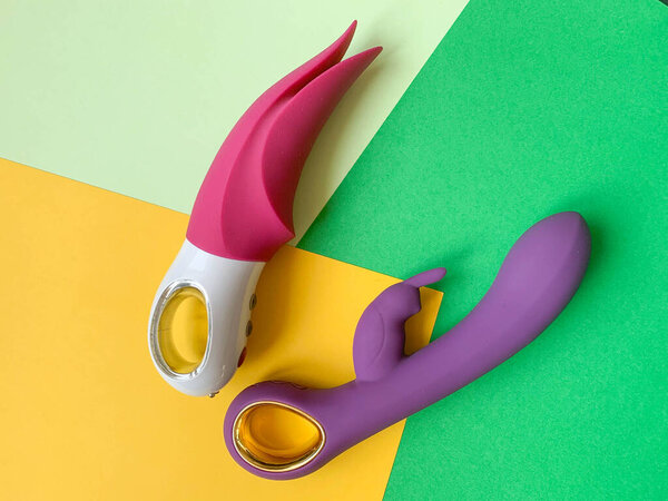 Секс-игрушки. Два вибратора на цветном фоне. Полезно для взрослых, секс-шоп