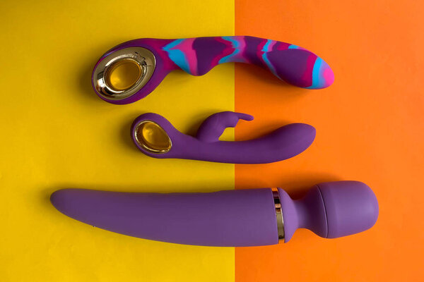 Sex toys. Three purple vibrators on a yellow background. Useful for sex shop, adult