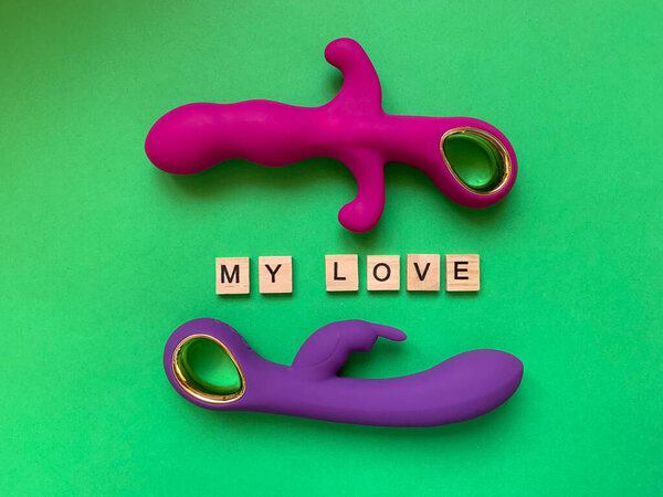 Sex toys. Two vibrators on a green background. Inscription MY LOVE. Useful for adult, sex shop