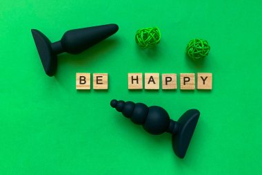 Sex toys. Two butt plug on a green background. Inscription BE HAPPY. Useful for adult, sex shop