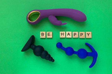 Sex toys. Two butt plug and vibrator on a green background. Inscription BE HAPPY. Useful for adult, sex shop