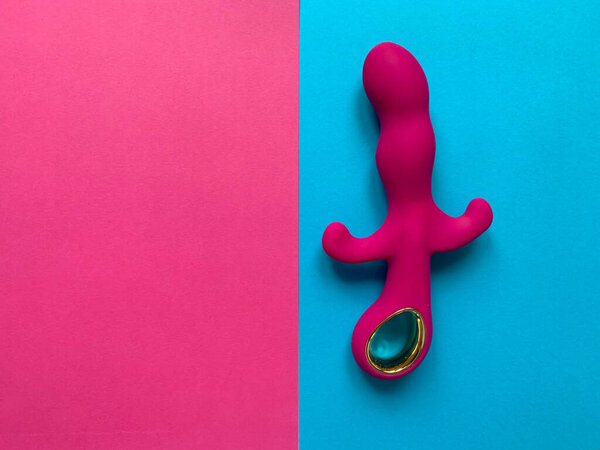Female toy. Pink vibrator on a pink and blue background. Useful for adult, sex shop