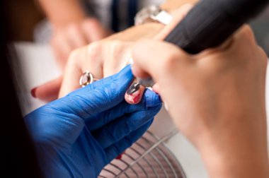 Bir kadın müşteri elleri üzerinde Manikürcü iş, onu çivi güzel görünmesi. Salon prosedürü devam ediyor. Sterilite için eldivenlerde profesyonel çalışmalar