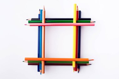 Beyaz bir arka plan üzerinde renkli kalemler çerçevesinde