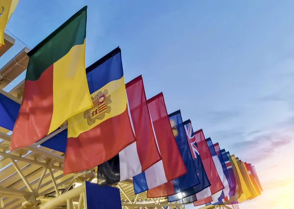 Farklı ülkelerin bayrakları günbatımı gökyüzünün arka planında