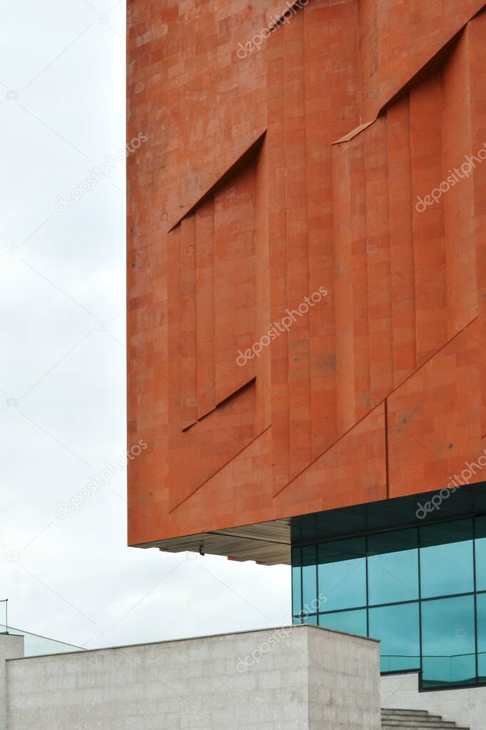 Detail of the wall of a neo constructivism building made of red brick and glass.