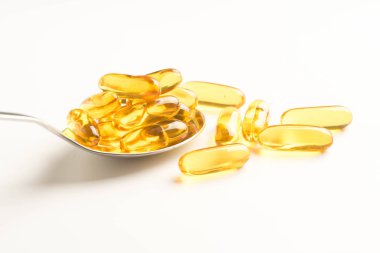 Balık yağı kapsülleri bir kaşık beyaz arka plan üzerinde