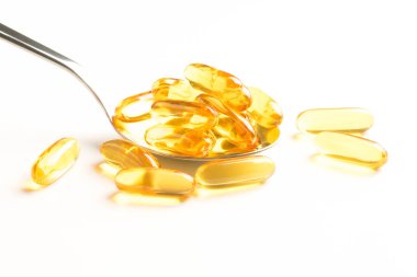 Balık yağı kapsülleri bir kaşık beyaz arka plan üzerinde