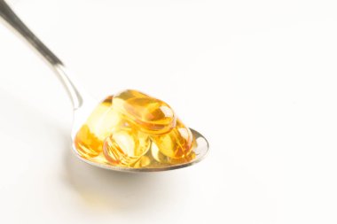 Balık yağı kapsülleri bir kaşık beyaz arka plan üzerinde