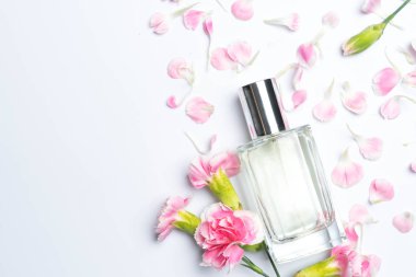Güzel parfüm şişeleri ve beyaz arka planda pembe karanfiller.