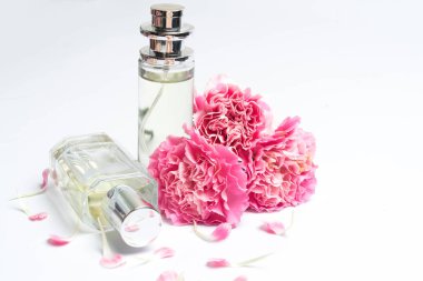 Güzel parfüm şişeleri ve beyaz arka planda pembe karanfiller.