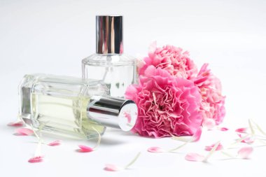 Güzel parfüm şişeleri ve beyaz arka planda pembe karanfiller.