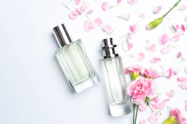 Güzel parfüm şişeleri ve beyaz arka planda pembe karanfiller.