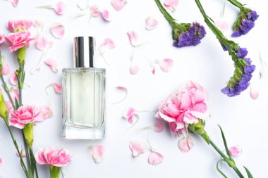 Güzel parfüm şişeleri ve beyaz arka planda pembe karanfiller.