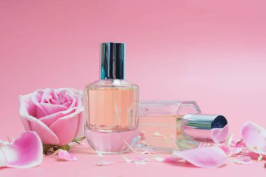 Parfüm şişeleri ve pembe arka plan üzerinde gül