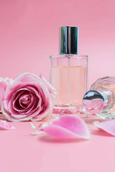 Frascos de perfume y rosa sobre fondo rosa — Foto de Stock