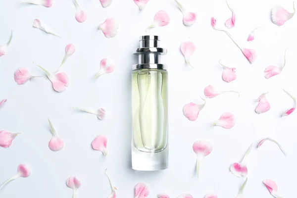 Frascos de perfume y claveles rosados sobre fondo blanco —  Fotos de Stock