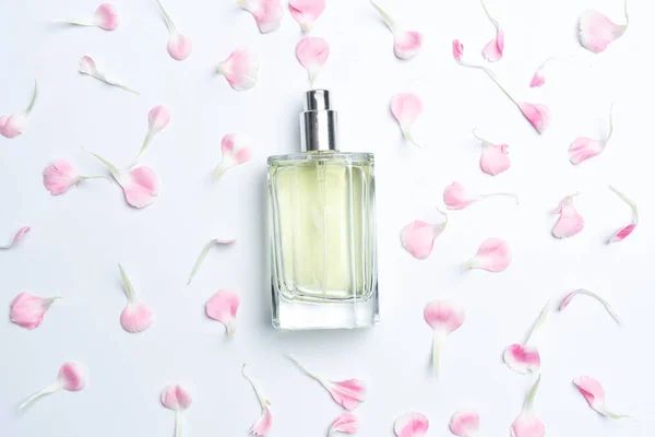 Parfümflaschen und rosa Nelken auf weißem Hintergrund — Stockfoto