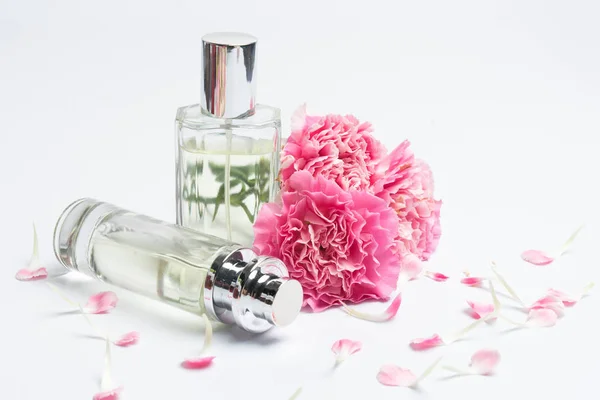 Butelki perfum i różowe goździki na białym tle — Zdjęcie stockowe