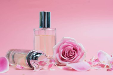 Parfüm şişeleri ve pembe arka plan üzerinde gül