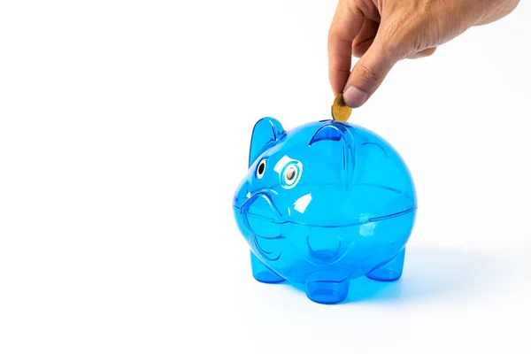 Mão colocando moeda no porquinho azul — Fotografia de Stock