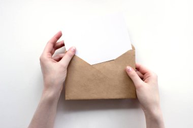 Zarf ve beyaz boş harf kadın ellerinin üst görüşünde. İletişim, bilgi, posta konsepti. Web, sosyal medya afişi şablonu. Stok fotoğrafı.