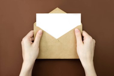 Zarf ve beyaz boş harf, kadınların elinde kopya alanı ile üst görünümü taklit ediyor. İletişim, bilgi, posta konsepti. Web, sosyal medya afişi şablonu. Stok fotoğrafı.