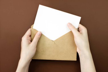 Zarf ve beyaz boş harf, kadınların elinde kopya alanı ile üst görünümü taklit ediyor. İletişim, bilgi, posta konsepti. Web, sosyal medya afişi şablonu. Stok fotoğrafı.