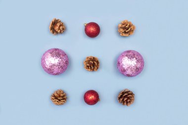 Kırmızı ve pembe noel süslemelerinden yapılmış kare ve köknar kozalakları mavi arka plan manzaralı ve fotokopi alanı olan yaratıcı düz yatıyordu. Noel kompozisyonu. Mutlu yıllar, xmas kutlaması konsepti.