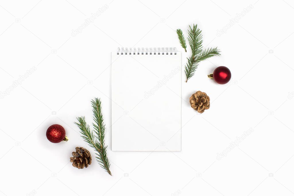 Notebook, fir cones, spruce branches, red decorations flat lay isolated on white background, copy space. Christmas to do list, goals, wishes, shopping list, planning. Happy new year, xmas celebration.