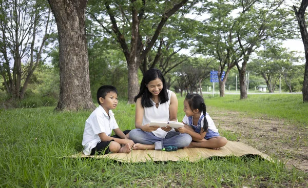 アジア系の家族 息子と娘が公園で読書活動を行う — ストック写真