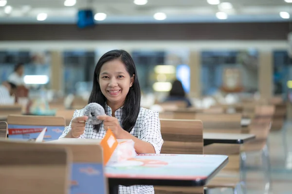 Asian women eat donuts at the shop happily.