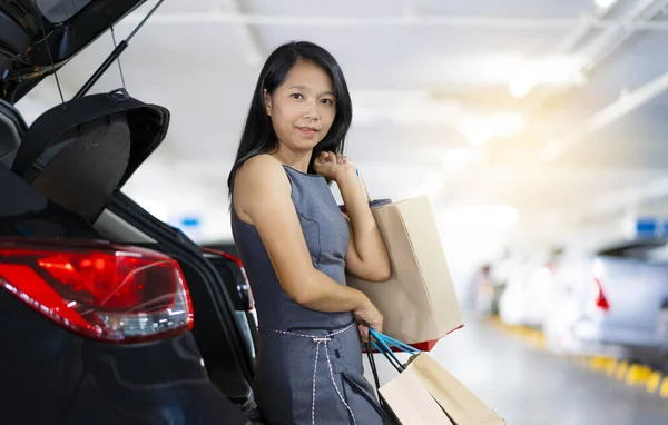 アジアの女性は 車の後ろの買い物袋をしてください 駐車場はショッピング モールです — ストック写真