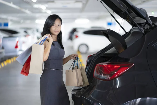 アジアの女性は 車の後ろの買い物袋をしてください 駐車場はショッピング モールです — ストック写真