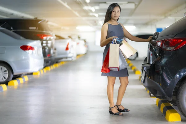 アジアの女性は 車の後ろの買い物袋をしてください 駐車場はショッピング モールです — ストック写真