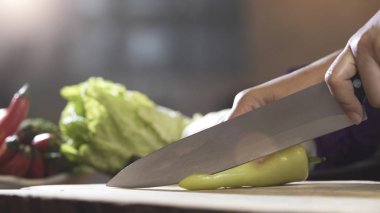 Chili ahşap tahta üzerinde mutfak bıçağı ile dilimleme, yakın çekim.