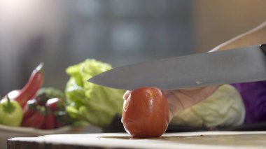 Domates ahşap tahta üzerinde mutfak bıçağı ile dilimleme, yakın çekim.