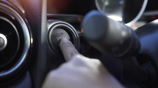 Feche a mão da mulher, ela aperta o botão iniciar no carro moderno . — Fotografia de Stock