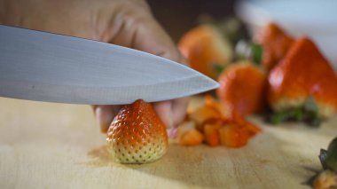 Bir bıçakla parçalara dilim taze çilek.