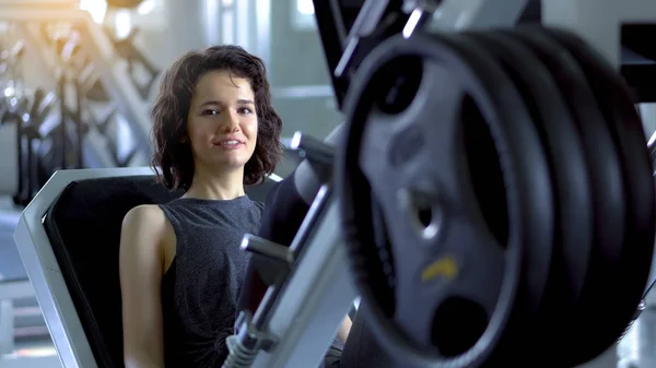 Joven mujer deportiva de entrenamiento por las piernas de prensa en el gimnasio, quads máquina — Foto de Stock