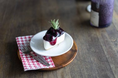 Ahşap bir masaya yerleştirilen bir tabakta yaban mersini kek