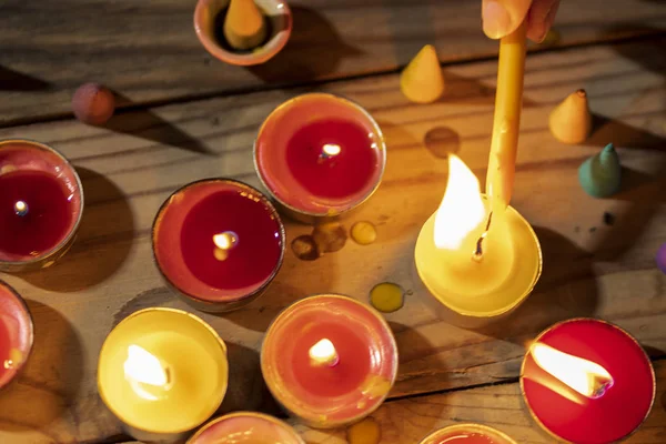 Bougie allumée à la main sur une table en bois. Beaucoup de flammes de bougie dans da — Photo