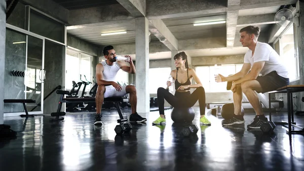 Group of young sporty people resting after working out in studio — Stockfoto