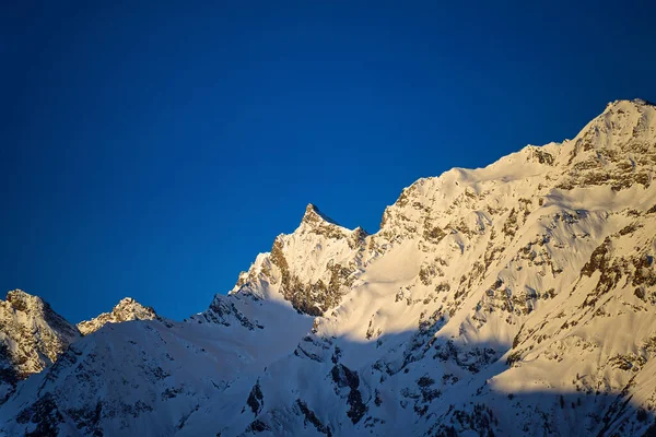 Los Primeros Rayos Sol Amanecer Iluminan Los Picos Nevados Los —  Fotos de Stock