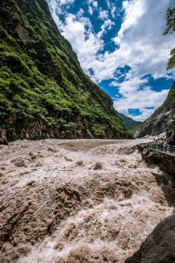 Yunnan, Çin 'deki Tiger Juming Vadisi' ndeki akıntılar. Çerçevenin en sağındaki tanınmayan çok küçük insanlar ölçek algısı veriyor.
